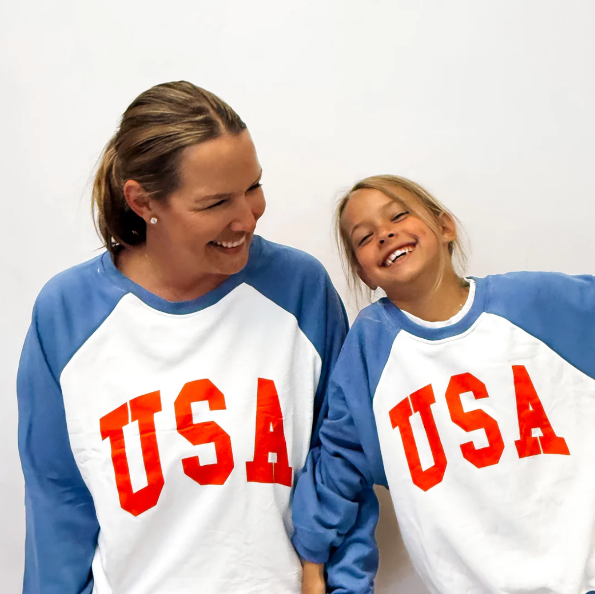 Two people wearing matching 'USA' sweatshirts against a white background