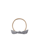 A light gray fabric bow headband with a tan elastic band, shown against a plain white background.