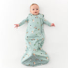 Baby in a light blue sleep sack with printed golf design on a white background