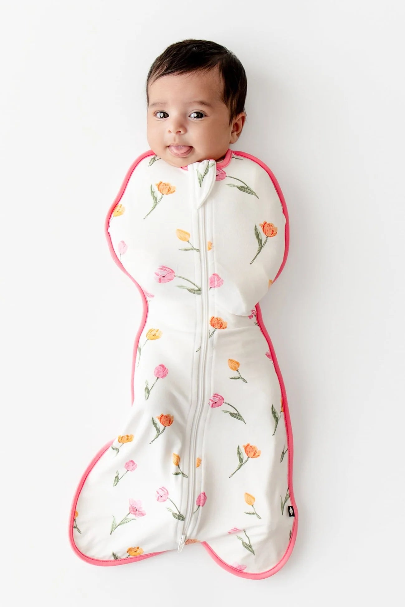 Baby in a floral-patterned sleep bag swaddle on a white background