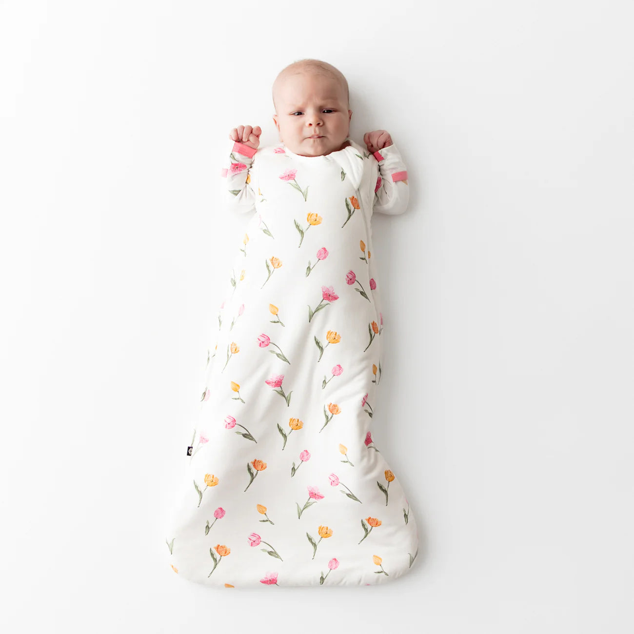 Baby wrapped in a floral-patterned sleep sack on a white background