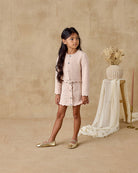 Young girl in a pink outfit standing in a studio with a neutral background