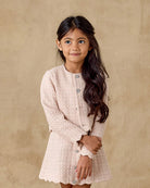 Young girl wearing a light pink dress against a beige background