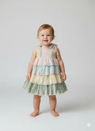 Child wearing a colorful tiered dress on a white background