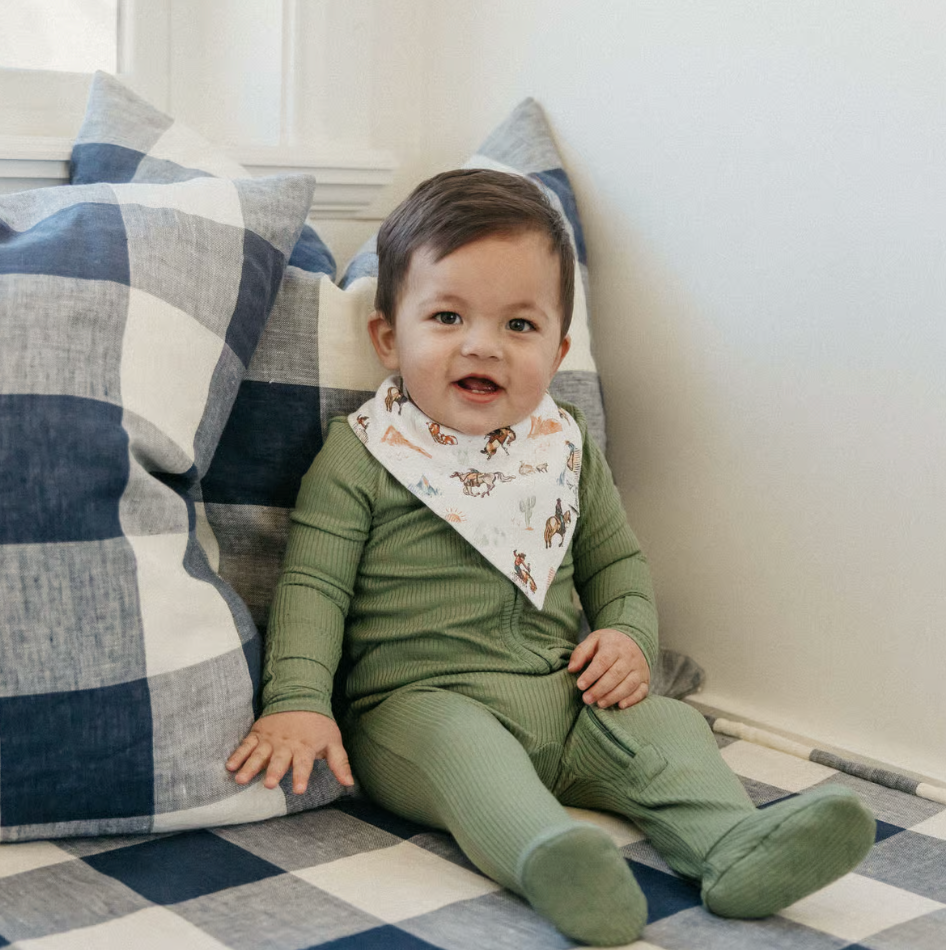 toddler in green pajamas and western bandana bib