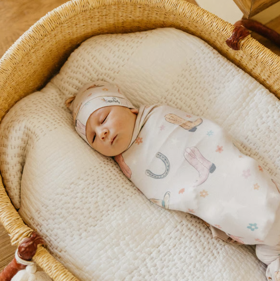 baby swaddled in cowgirl print swaddle with matching hat 