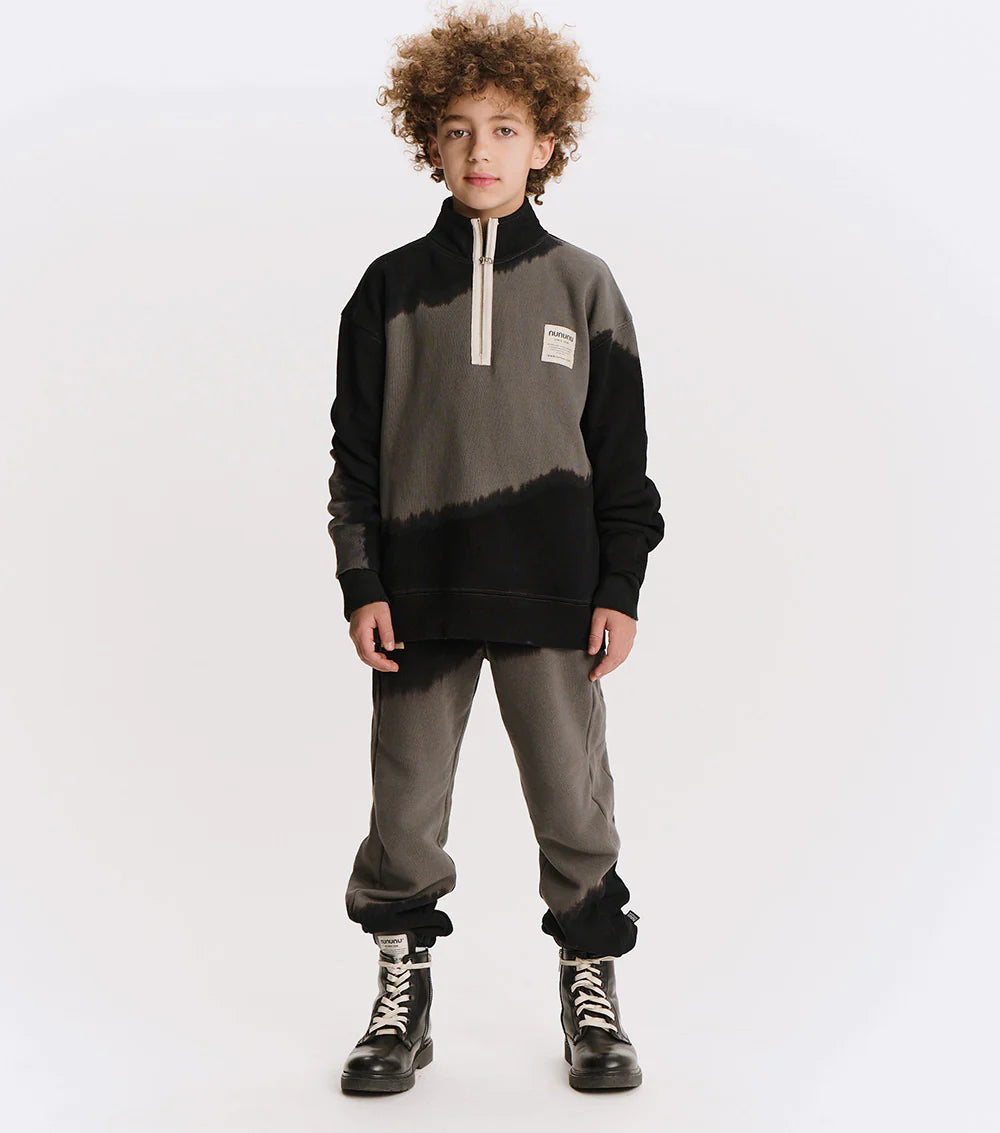 Person wearing a black and gray gradient sweater with a white background