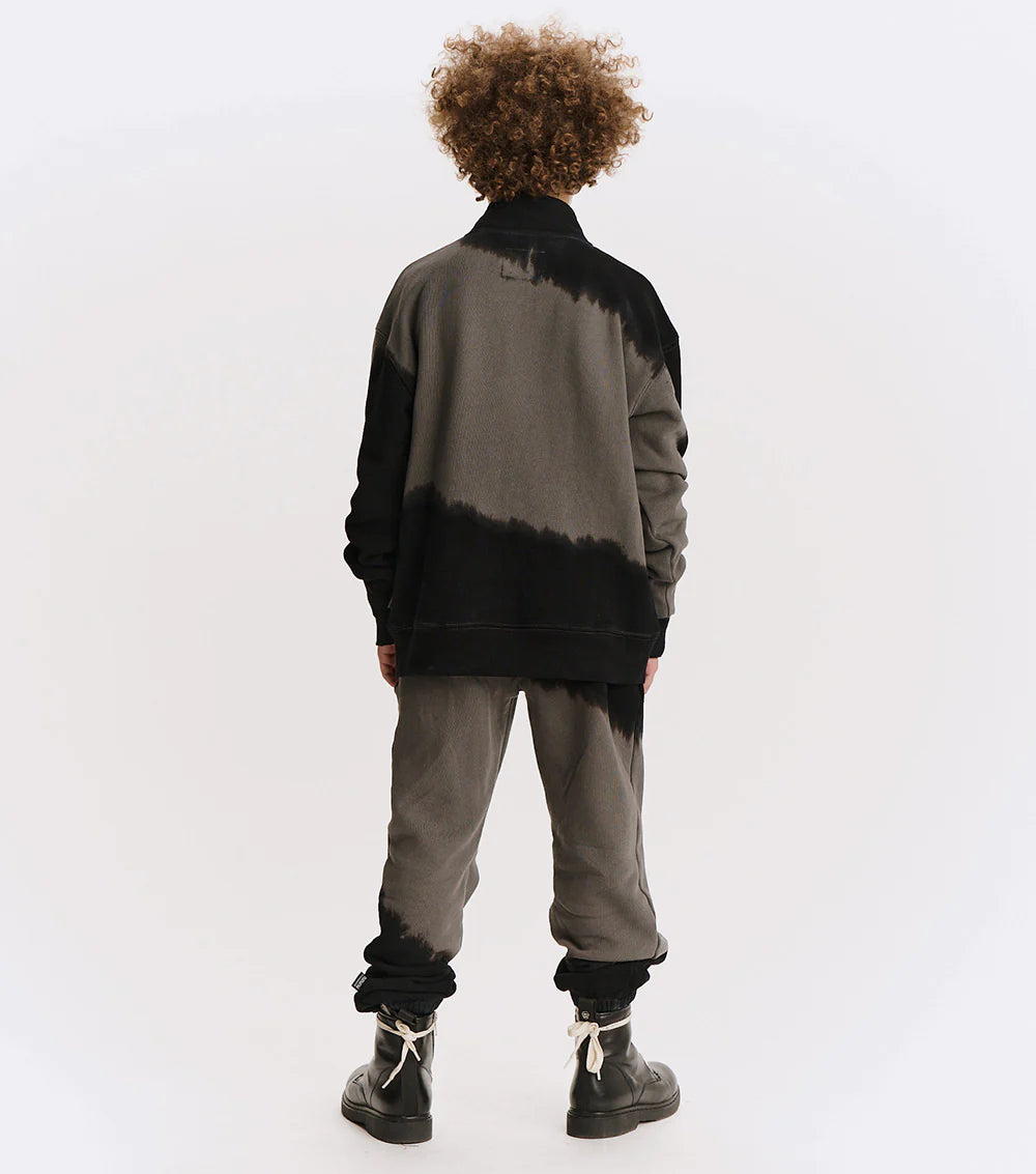 Person wearing a black and gray gradient jacket with matching pants on a white background