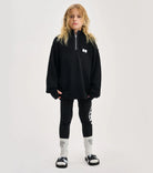 child in leggings and black quarter zip sweatshirt