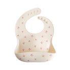 Beige silicone bib with bow patterns on a white background