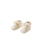 Pair of cream baby shoes with bows on a white background