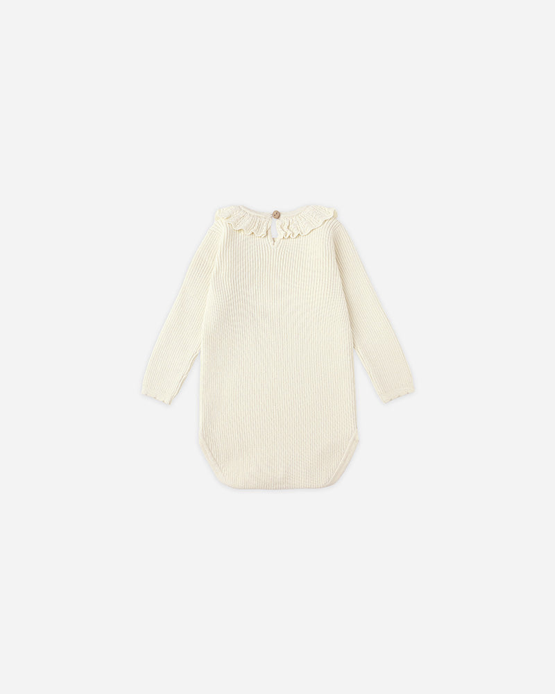 Cream-colored baby outfit with long sleeves on a white background