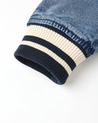 Close-up of a denim sleeve with striped cuffs on a white background