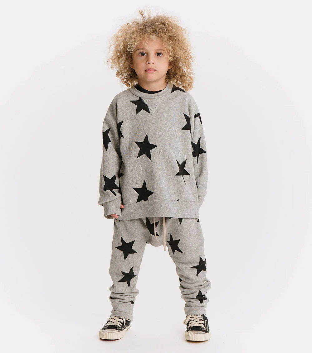 Child wearing a gray sweatshirt and pants with black star patterns on a white background