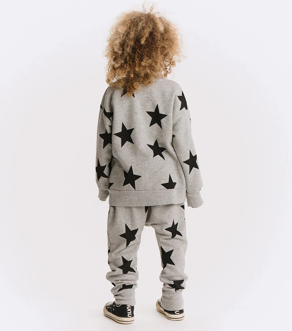 Child wearing a gray outfit with black star patterns on a white background
