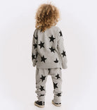 Child wearing a gray outfit with black star patterns on a white background