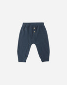 Navy blue baby pants with button details on a light gray background