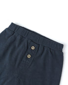 Navy blue pants with button details on a white background
