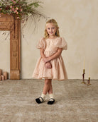 Young girl in a pink dress with black polka dots and puffy sleeves