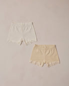 Two pairs of lace-trimmed shorts on a beige background
