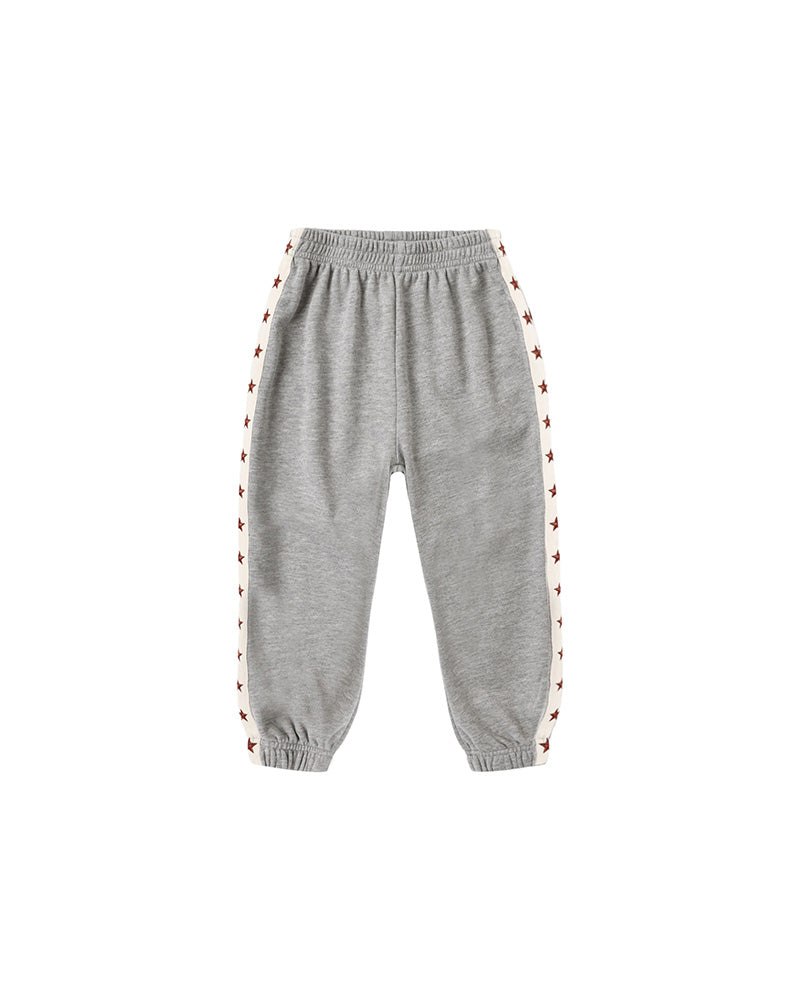 A pair of heather gray jogger sweatpants with white side stripes featuring a repeating red star pattern, shown against a plain white background.