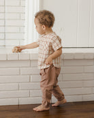 Brown children's pants with pockets, buttons, and an elastic waistband on a white background.