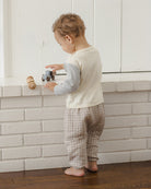 A pair of baby pants in a light gray and white plaid pattern, featuring an elastic waistband and elasticized leg cuffs, shown against a plain white background.