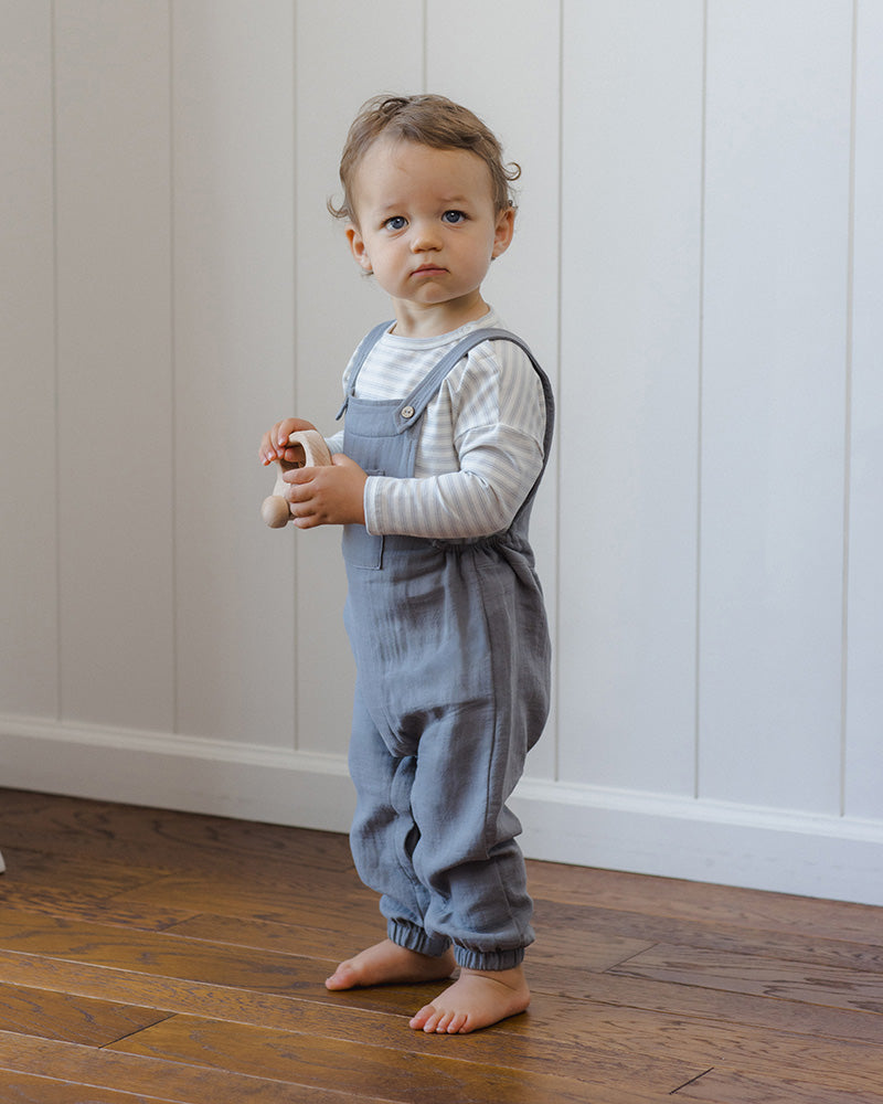 A pair of baby boy's gray linen bib overalls with elastic cuffed legs and adjustable shoulder straps, shown flat on a white background.