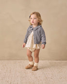 A gray knit cardigan sweater for toddlers, featuring a ruffled Peter Pan collar, long sleeves, and brown wooden buttons down the front, displayed on a clean white background.