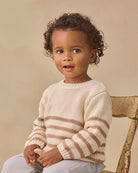 A cream-colored knit sweater with horizontal brown stripes across the chest and sleeves, displayed flat against a solid white background.