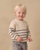 A cream-colored knit sweater with horizontal gray stripes across the lower half and sleeves, featuring a three-button henley neckline, shown against a plain white background.