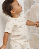 Child wearing a white shirt with small construction prints against a neutral background