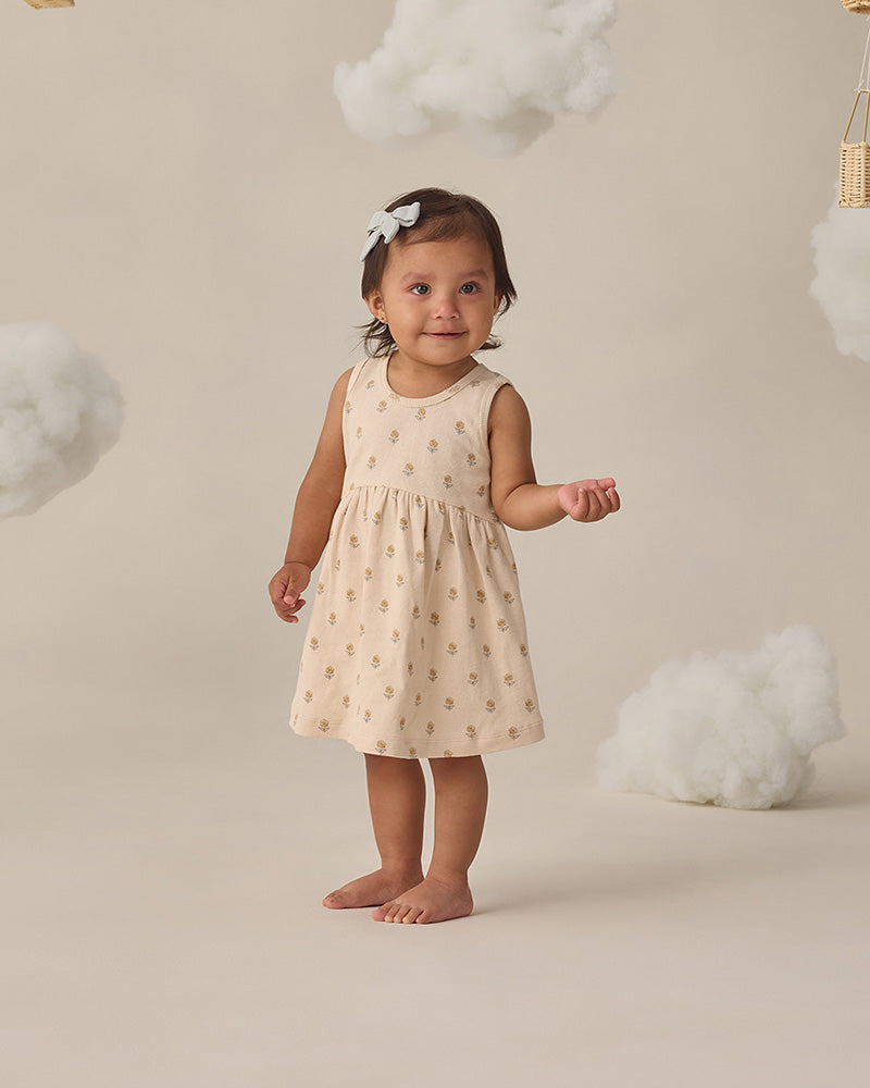Young child in a beige dress and floral patterns on a white background
