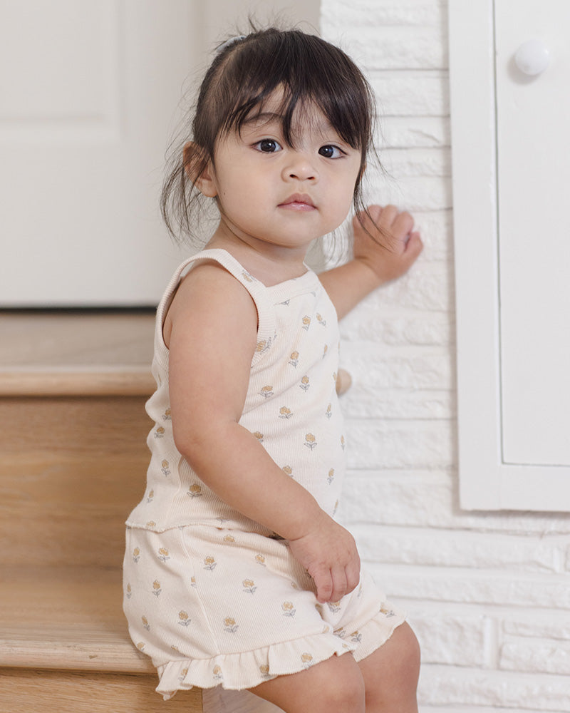 Little girl in white two piece set with floral and ruffle detailing