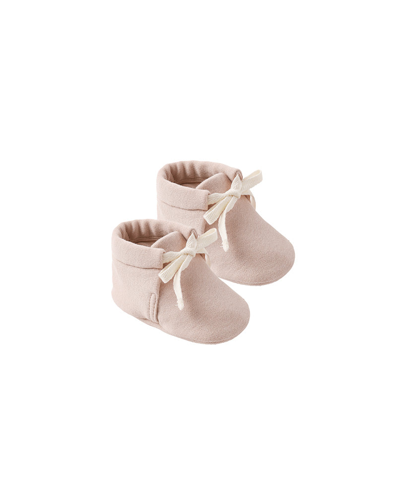 Pair of light pink baby booties with white laces on a white background