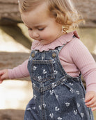 Blue denim overalls with floral pattern and front pocket on a white background