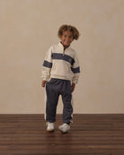 Black cuffed jogger pants with white side stripes on a white background