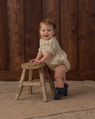 Baby romper with floral pattern and a ruffled collar and sleeves on a white background