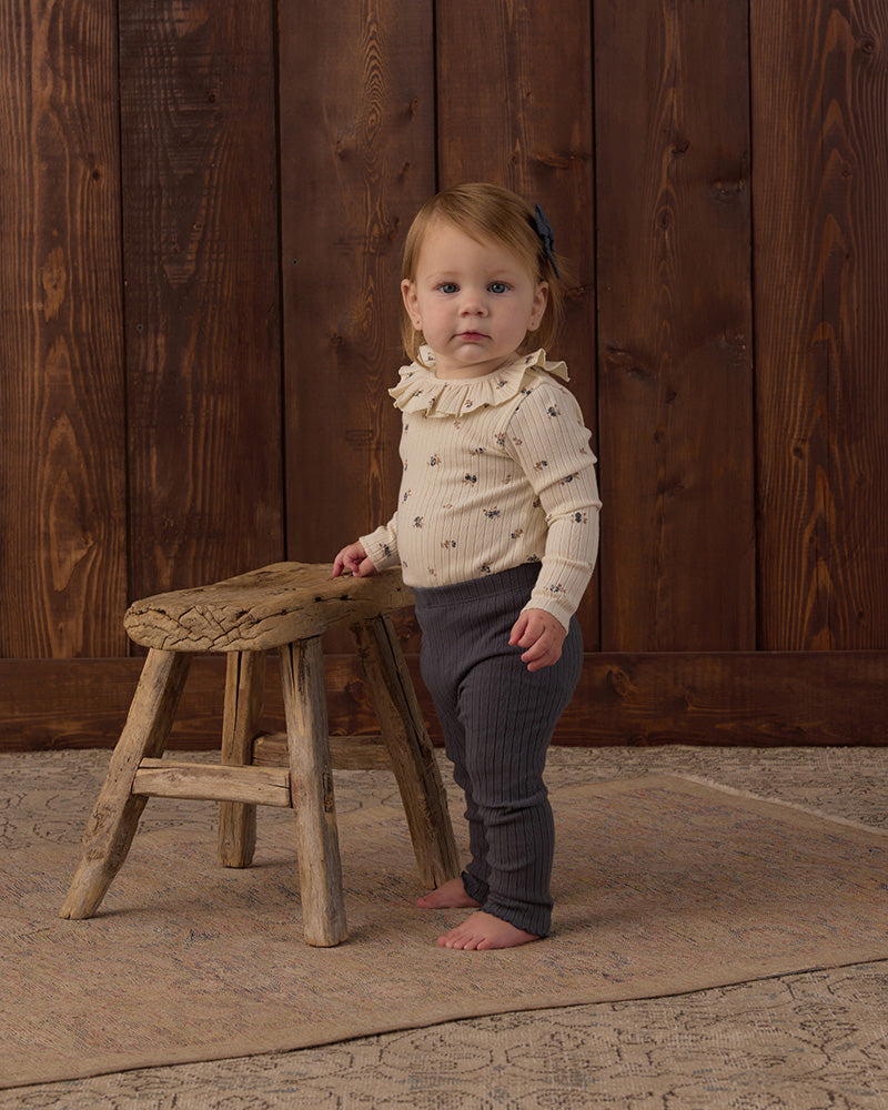 Dark ribbed leggings with ruffle detail on bottom against a white background