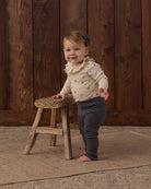 Baby onesie with floral pattern and a ruffled collar on a white background