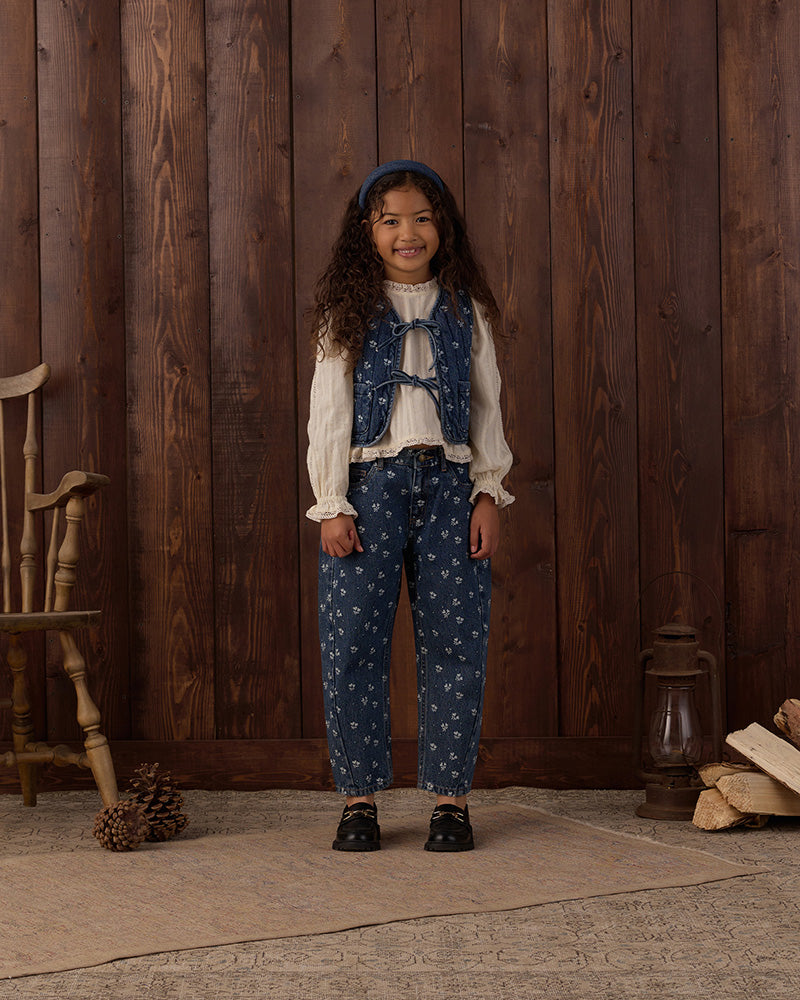 Denim vest with floral pattern and a bow tie front with pockets on a white background