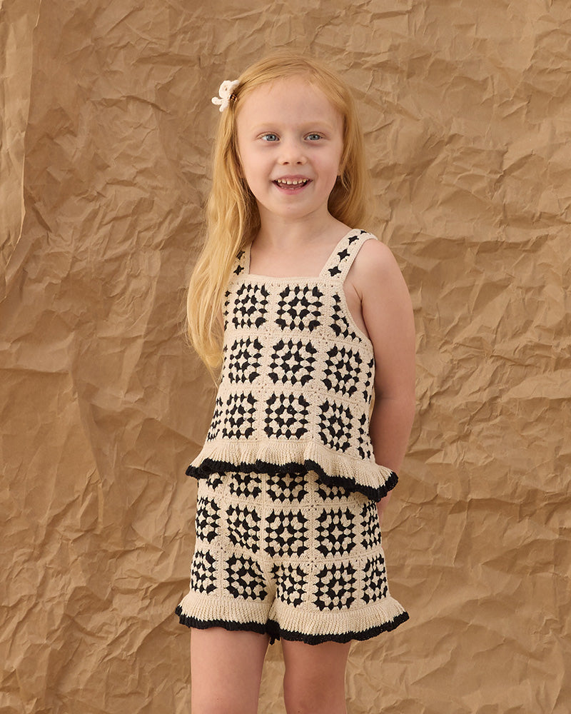 Young girl wearing a black and white patterned abstract outfit with a black ruffle trim