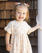 Young girl in a fruit patterned dress with ruffled sleeves