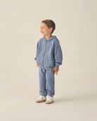 Child wearing a blue tracksuit on a beige background