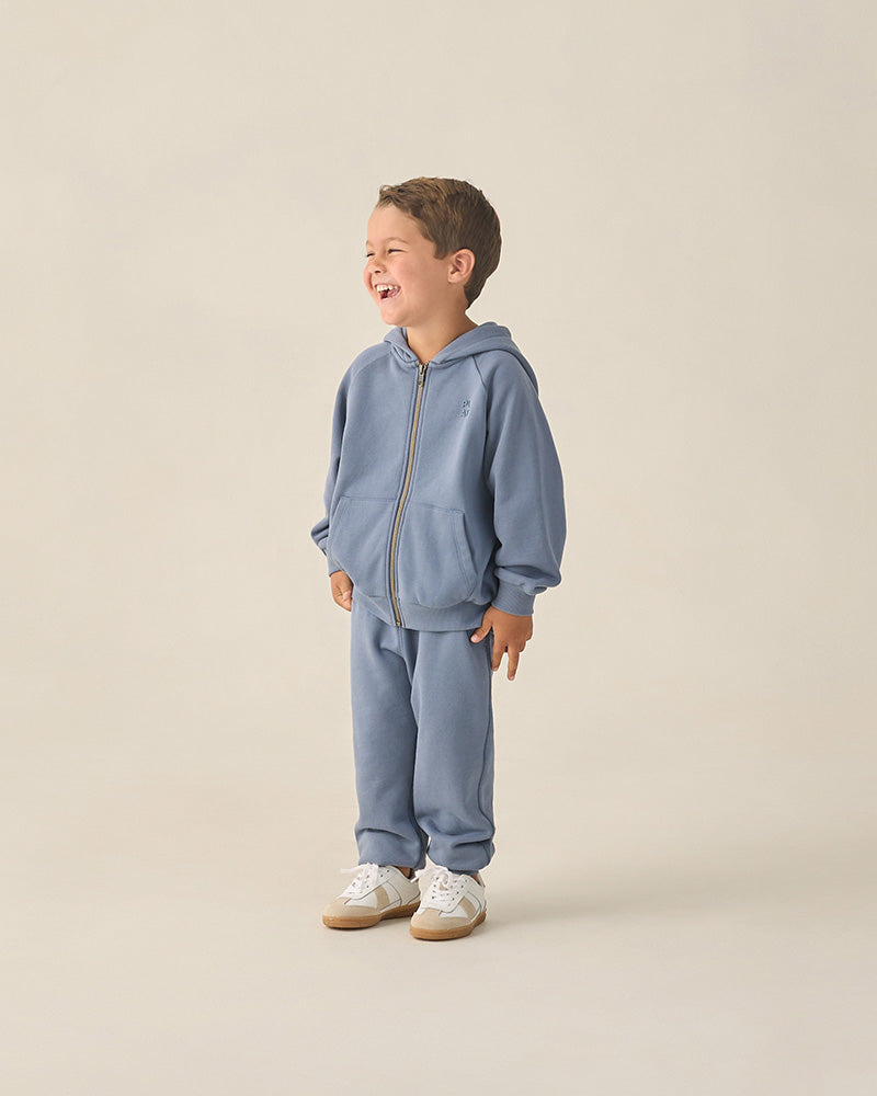 Child wearing a blue tracksuit on a beige background