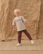 Child wearing a striped shirt with chocolate brown pants