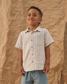 Child wearing a striped button up shirt against a textured brown background