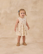 Young child wearing a nautical patterned  dress on a beige background