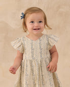 Child wearing a floral dress against a beige background