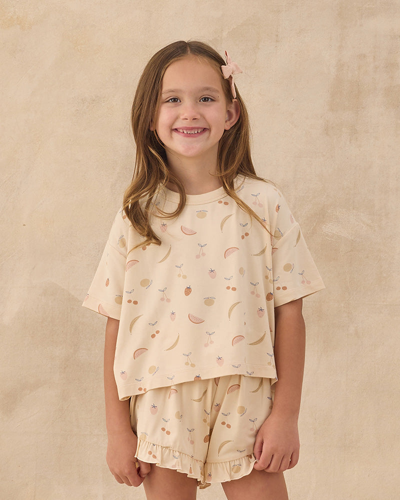 Young girl wearing a matching top and shorts set with assorted fruits